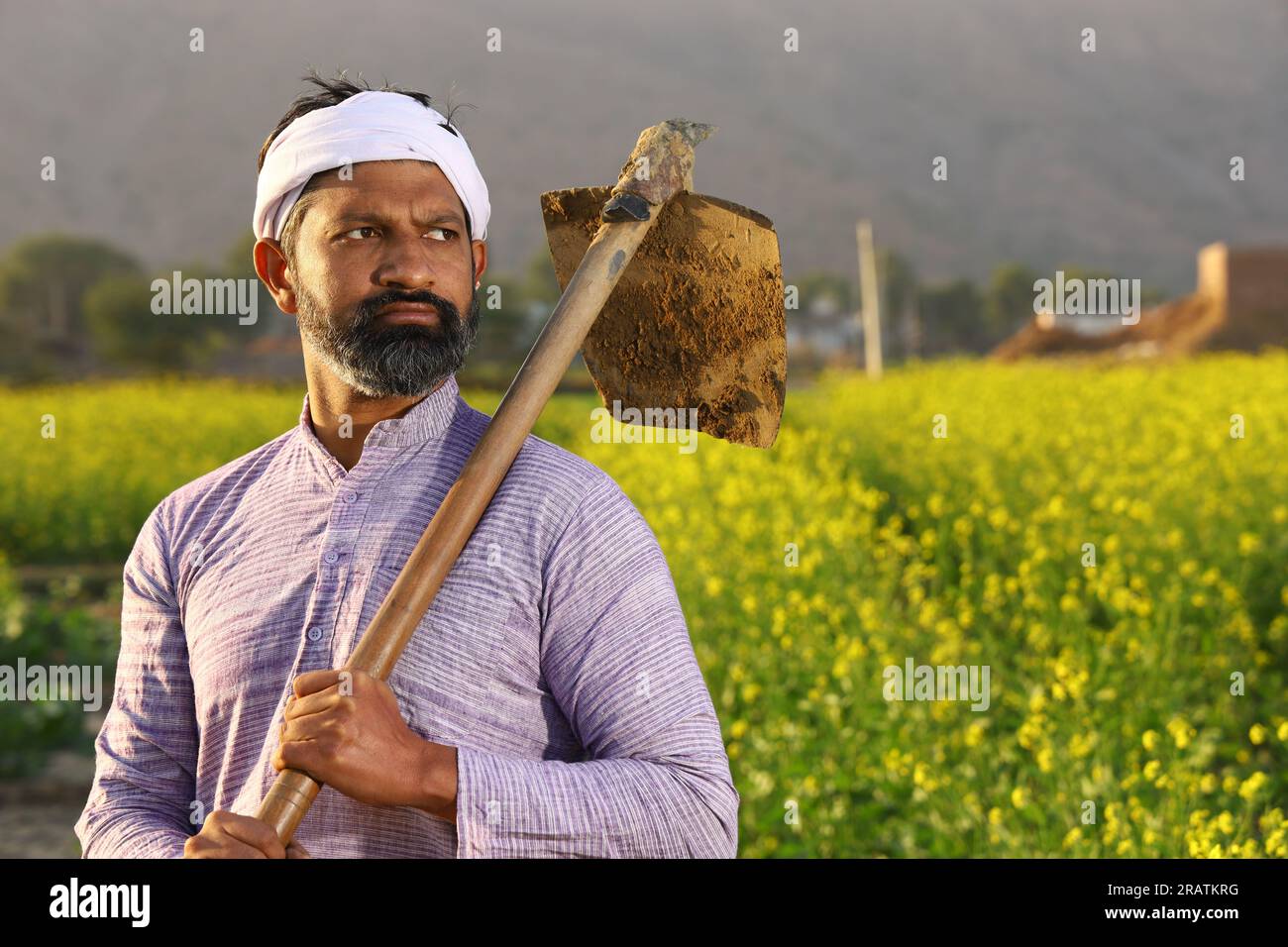 Angry bearded Indian farmer in turban standing with a shovel in his hand wearing Kurta pyjama. Stock Photo