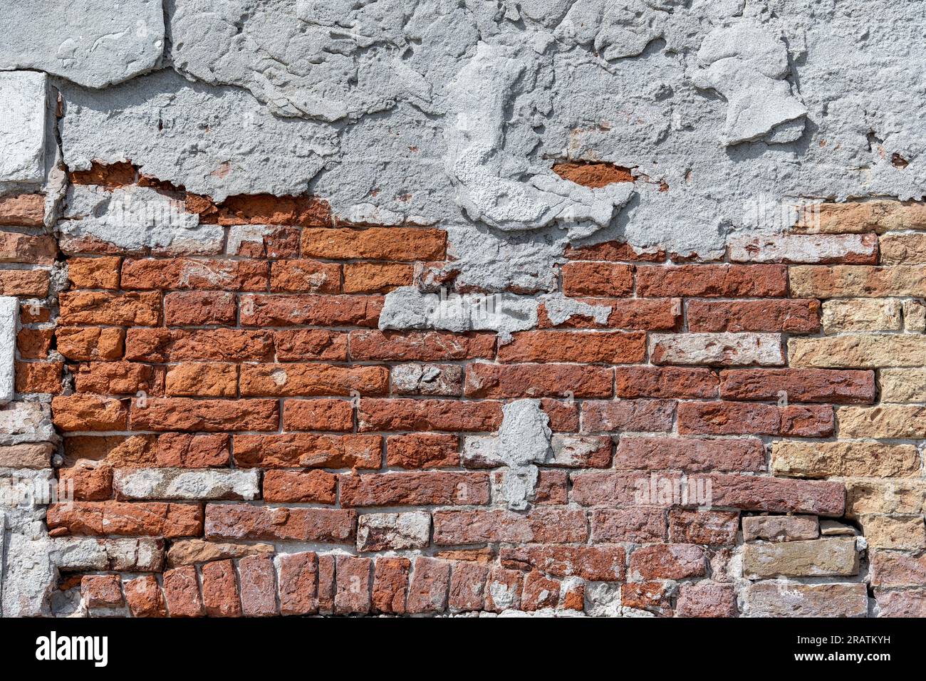 Plaster peeling from an old red brick wall. Worn out building in Venice