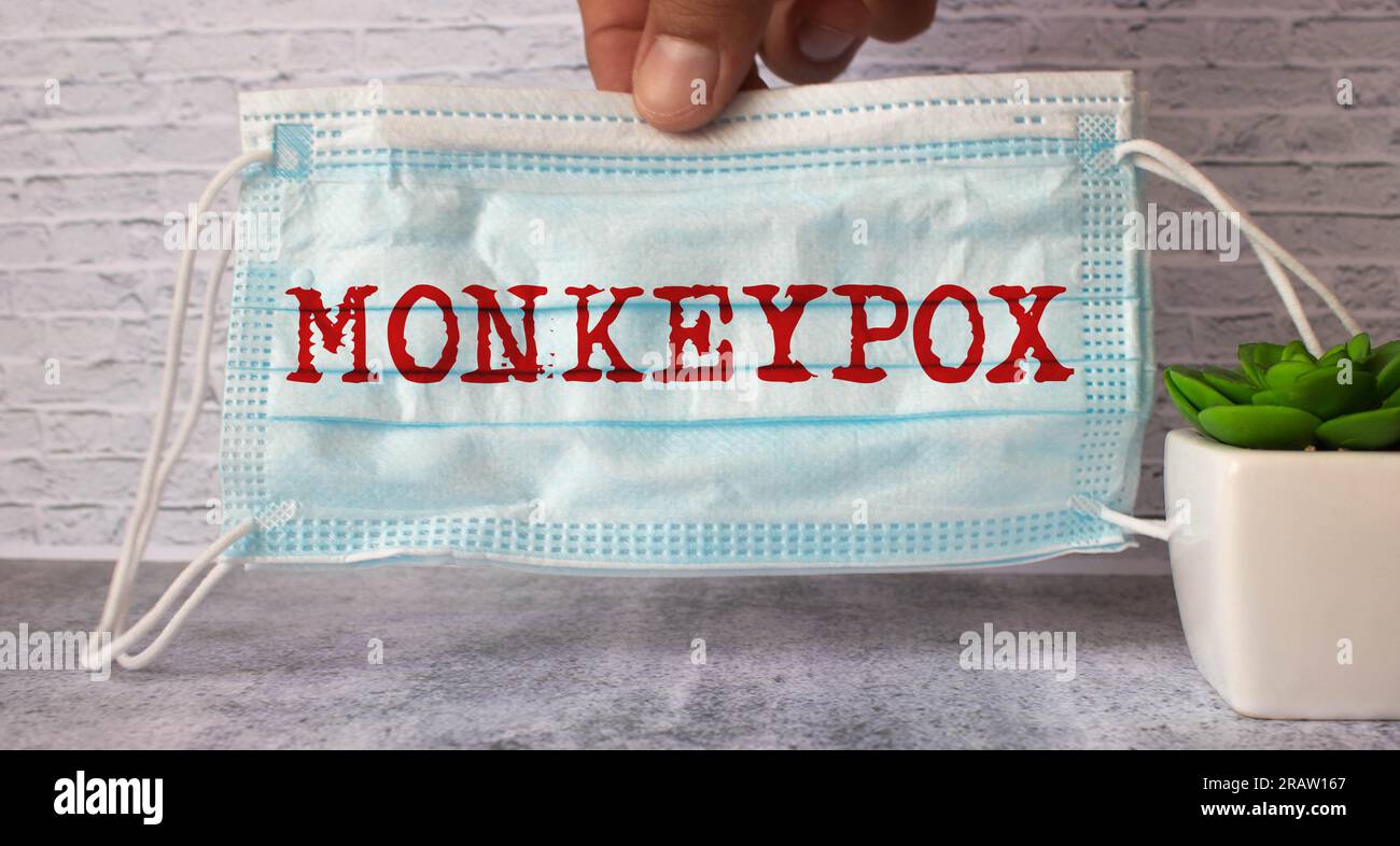 The doctor is holding a blue sheet of paper with the word MONKEYPOX written on it. Doctor's hand in protective gloves with a poster. Layout. Poster. B Stock Photo