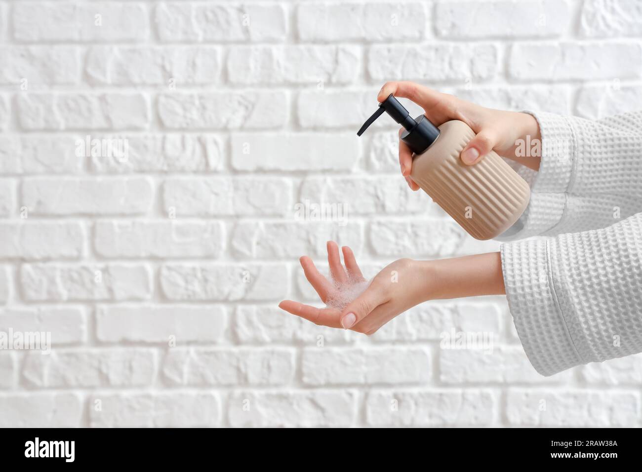 Hands with liquid soap on white brick background Stock Photo