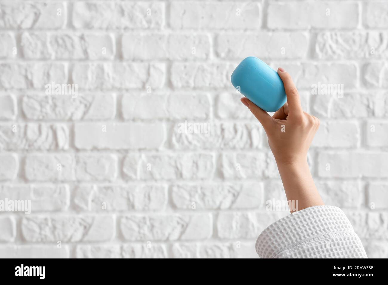 Hand with soap on white brick background Stock Photo