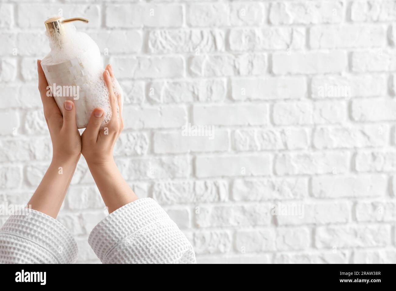 Hands with liquid soap on white brick background Stock Photo
