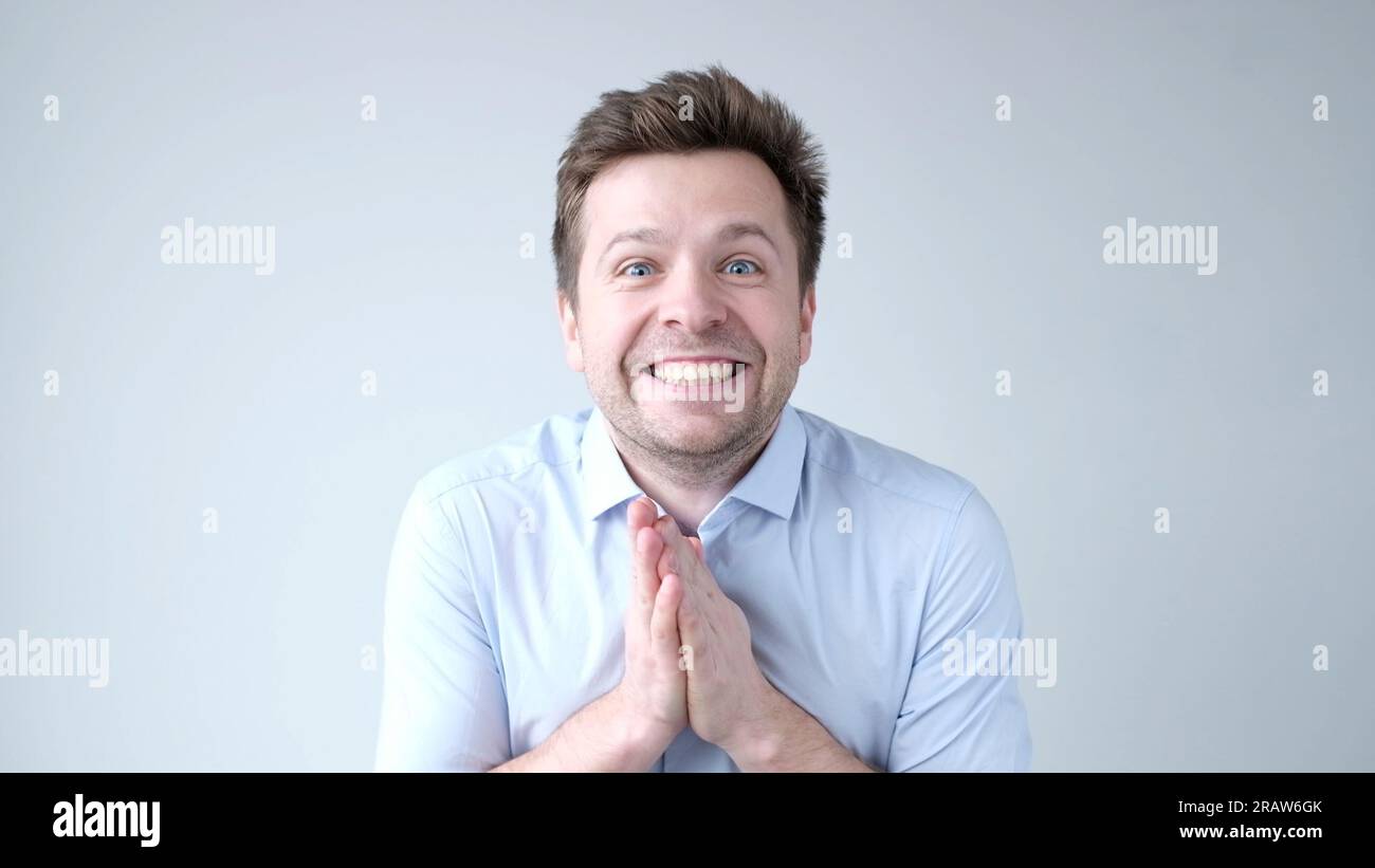 The young man, in awe, claps his hands, saying wow Stock Photo