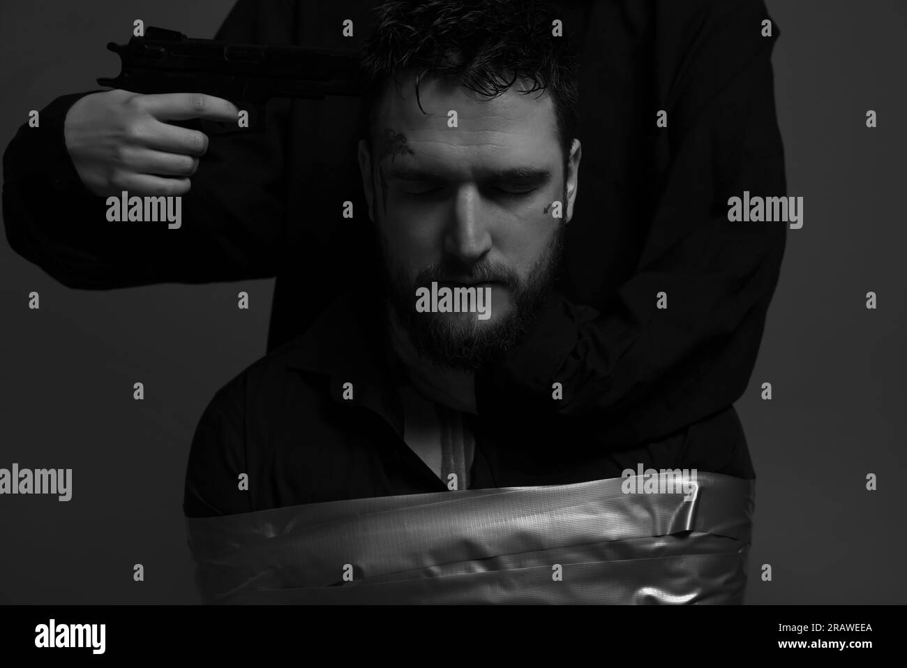 Kidnapper pointing gun at taped up man taken as hostage on grey