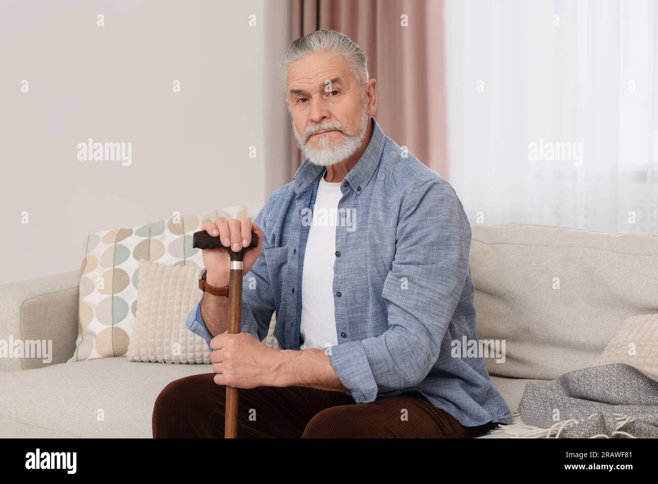 Senior man with walking cane sitting on sofa at home Stock Photo - Alamy