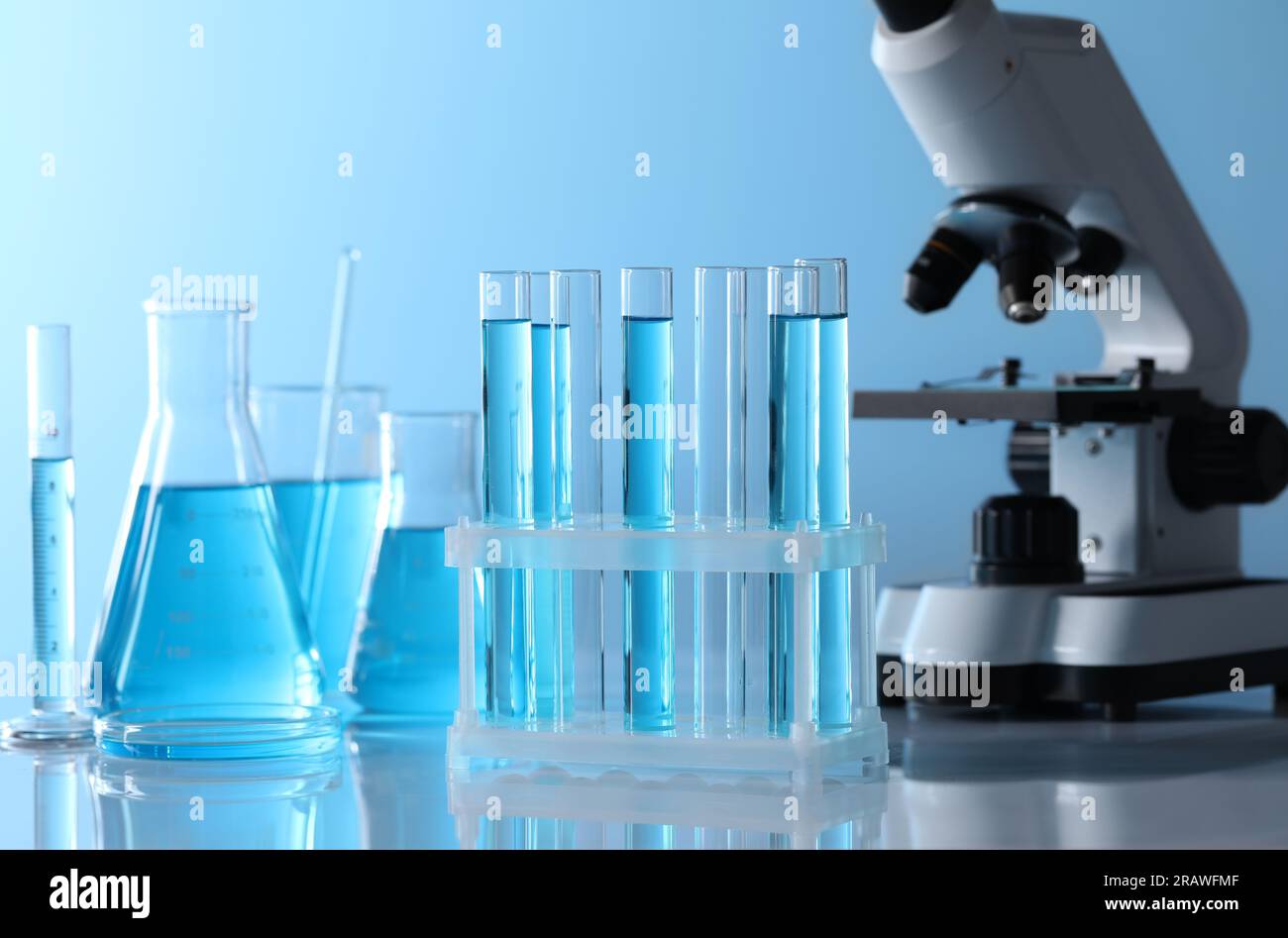 Microscope near different laboratory glassware and test tubes with ...