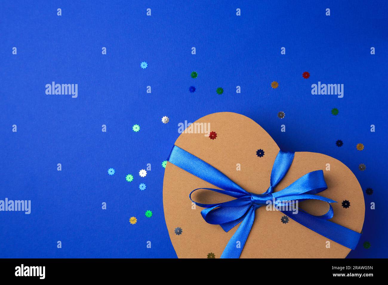 Beautiful heart shaped gift box with bow and confetti on blue ...