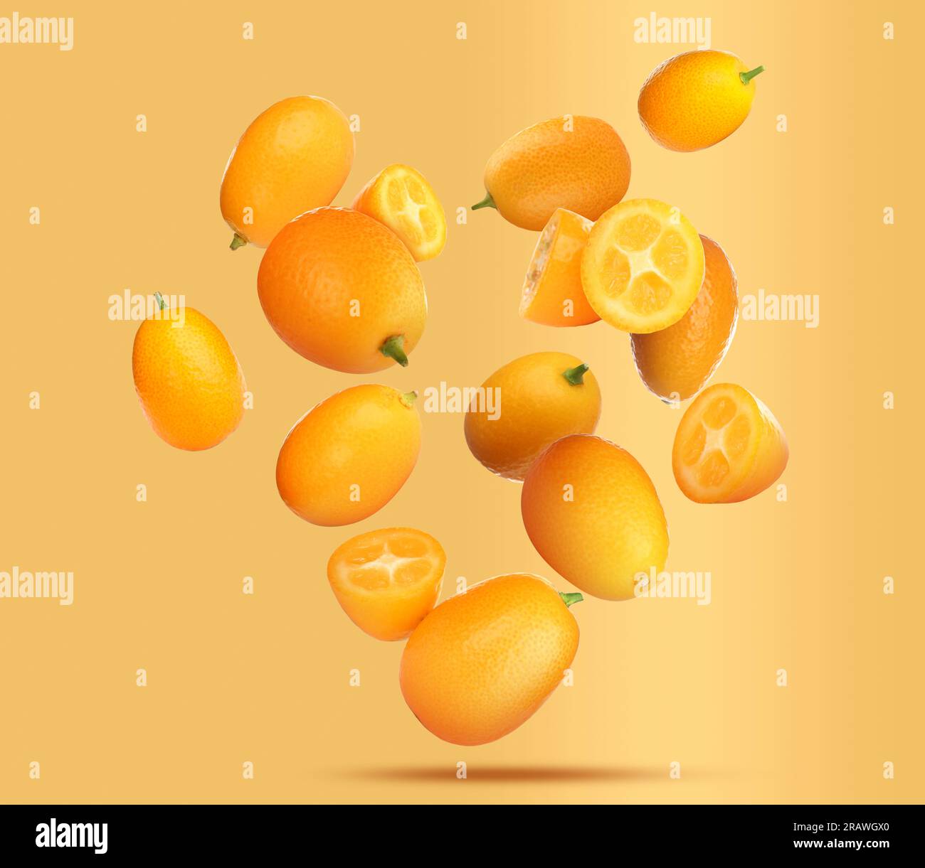 Delicious whole and cut kumquats falling on pale orange background