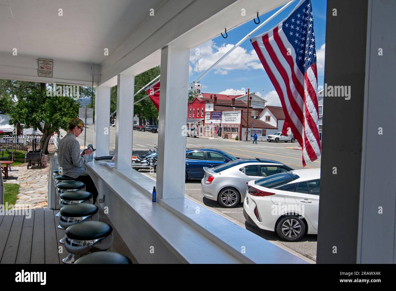A man sits at an outdoor counter at the historic Bridgeport Inn overlooking the Main Street of small-town Bridgeport, California Stock Photo