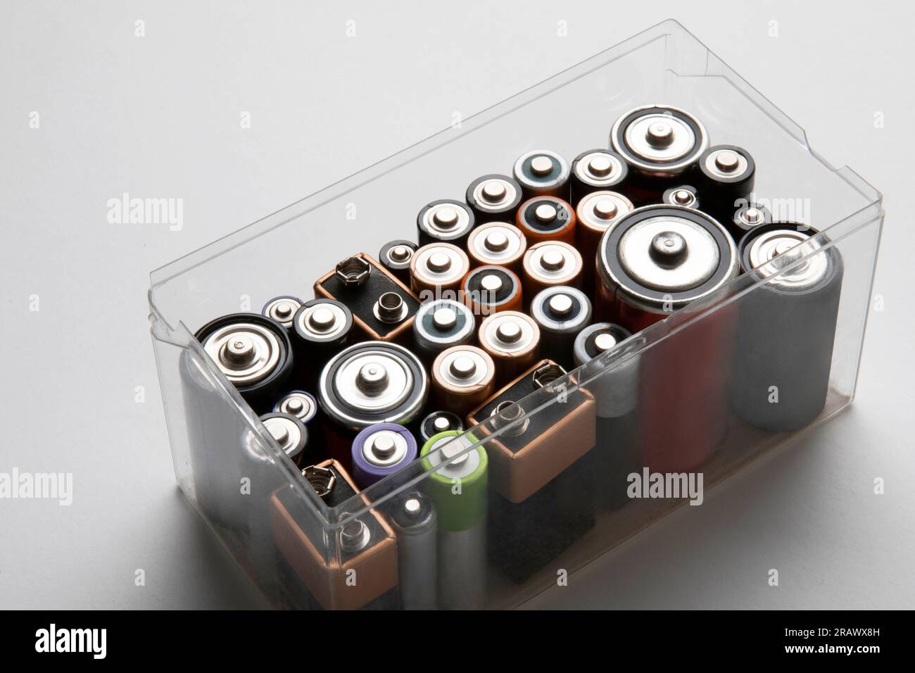 Used coloured batteries in a plastic container on white background