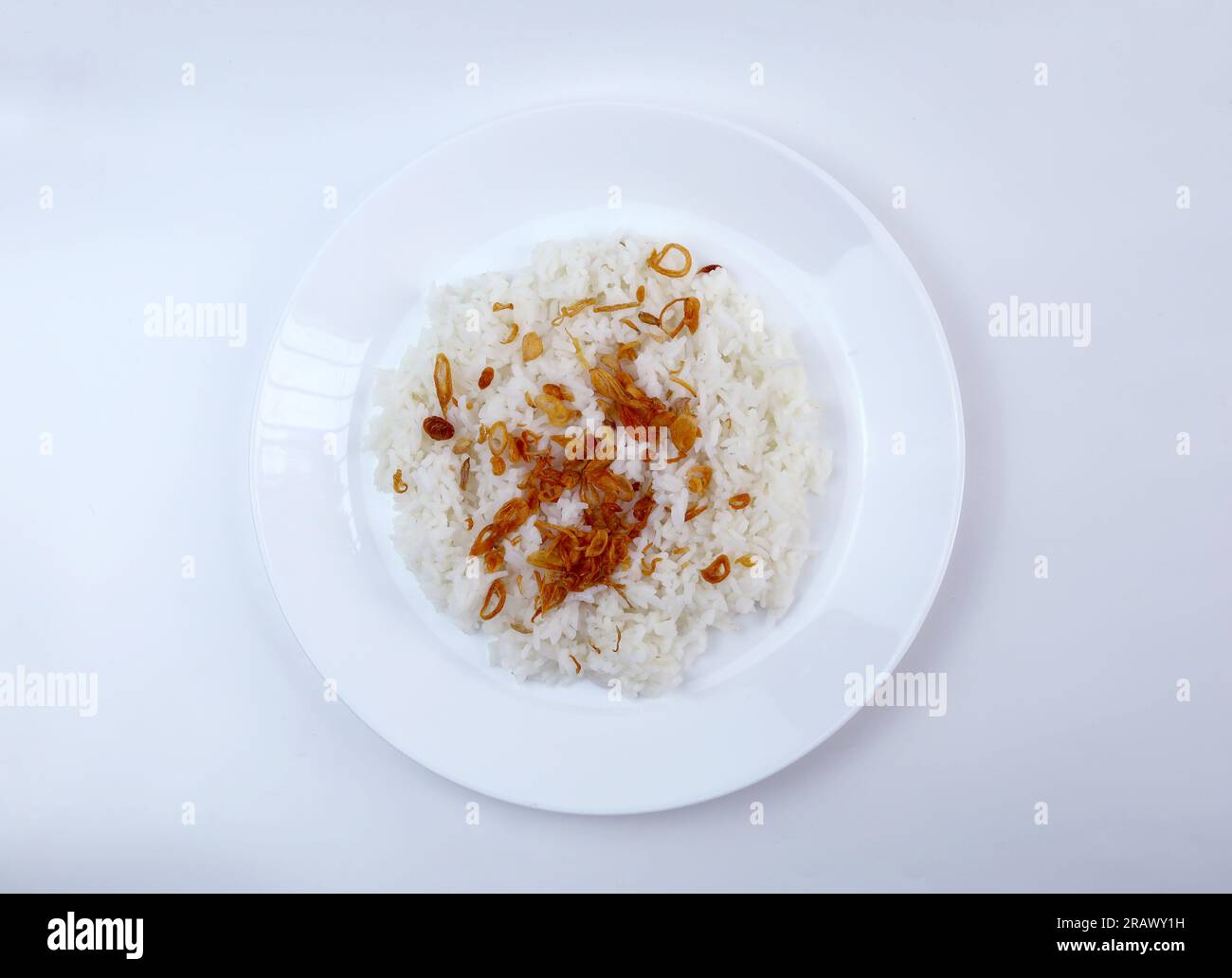 Top view a plate of warm white rice topped with fried onions. Concept for Asian comfort food. Stock Photo