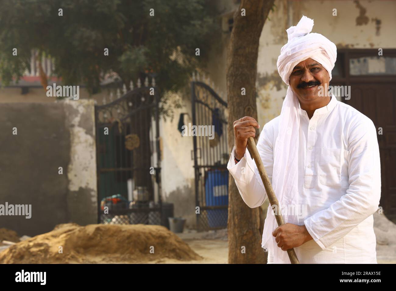 Mid-Aged man in Rural Environment wearing kurta-pajama which is traditional Dress for men in North India in day time holding walking cane. Stock Photo