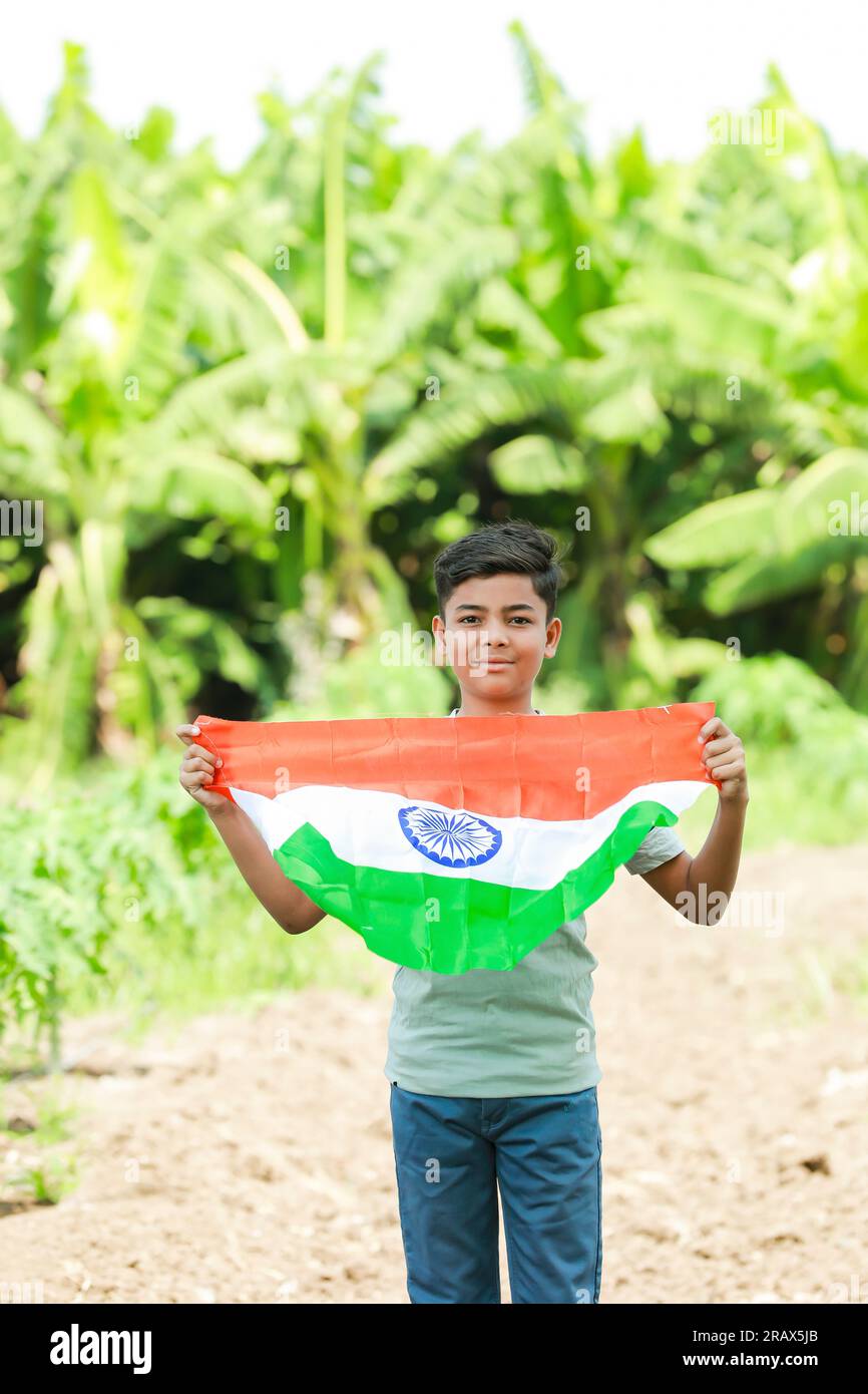 Indian boy holding national flag in farm, happy boy, national flag, poor kids Stock Photo