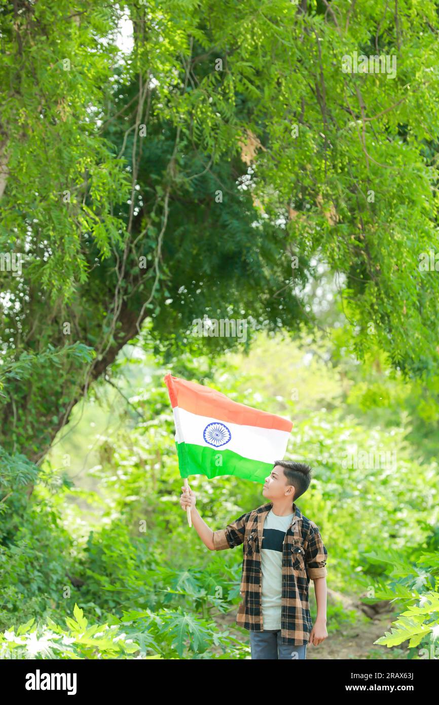 Indian boy holding national flag in farm, happy boy, national flag, poor kids Stock Photo
