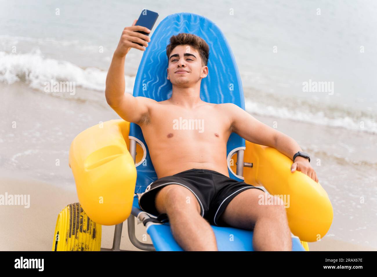 Man rescued by lifeguard taking a selfie sitting on a floating chair Stock Photo