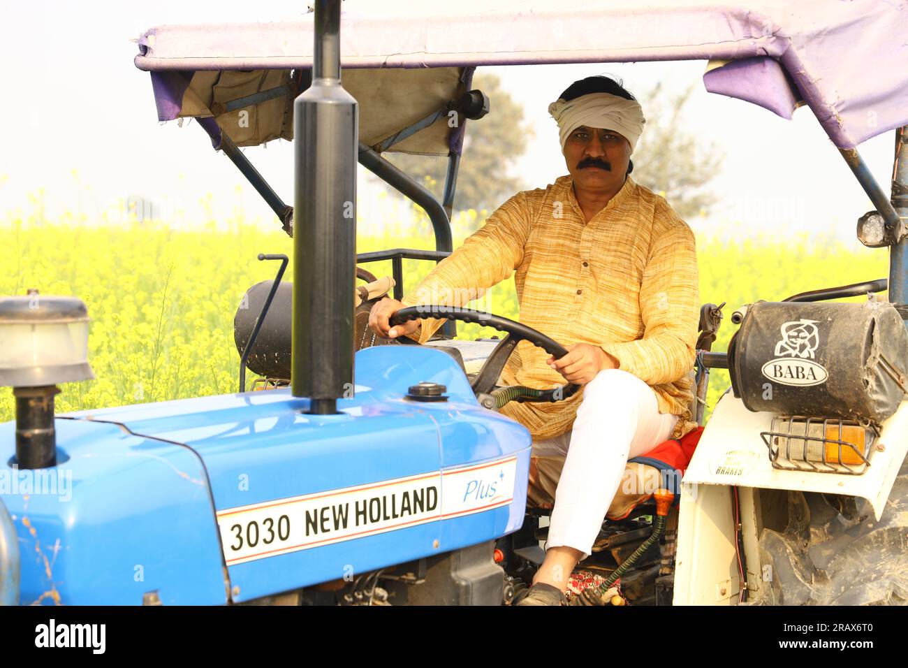Happy Indian villager farmer sitting on the tractor enjoying the village life. Stock Photo