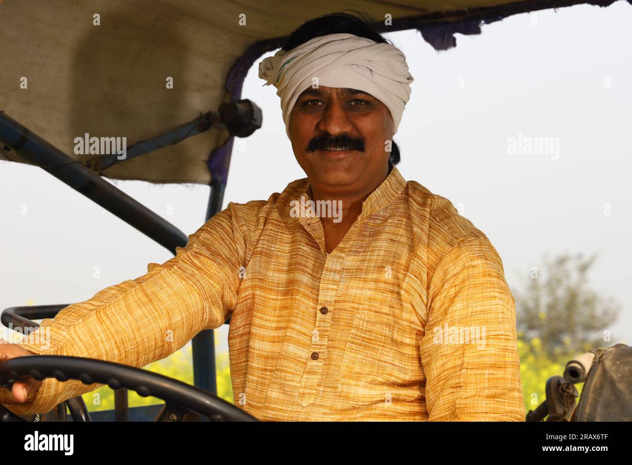 Happy Indian villager farmer sitting on the tractor enjoying the village life. Stock Photo