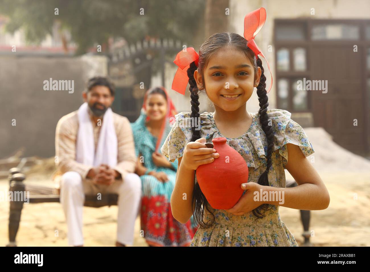 Happy rural Indian family sitting together, daughter is holding a piggy ...