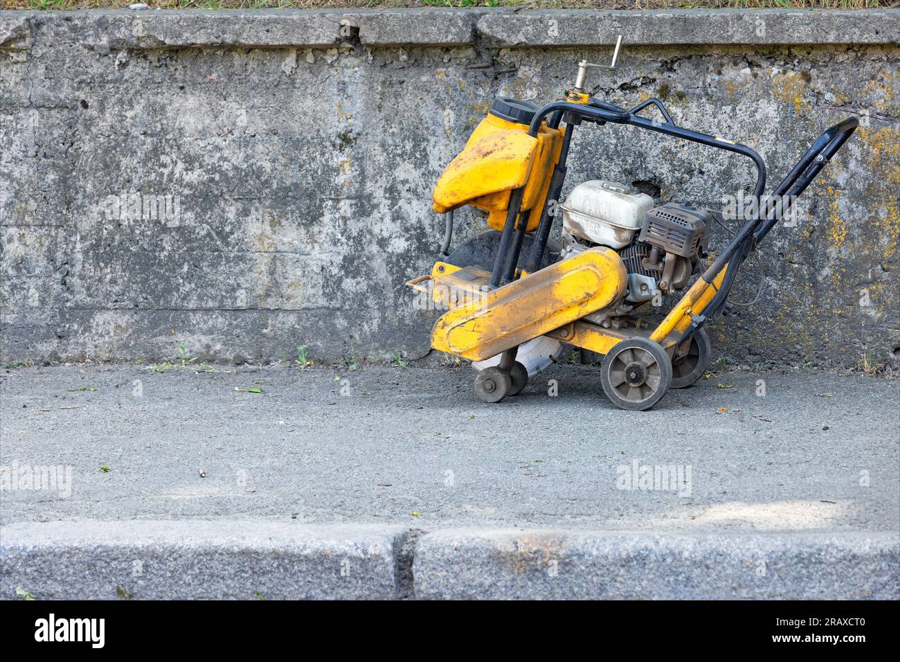 An old petrol cutter with a diamond cutting blade against a weathered concrete wall. Copy space. Stock Photo