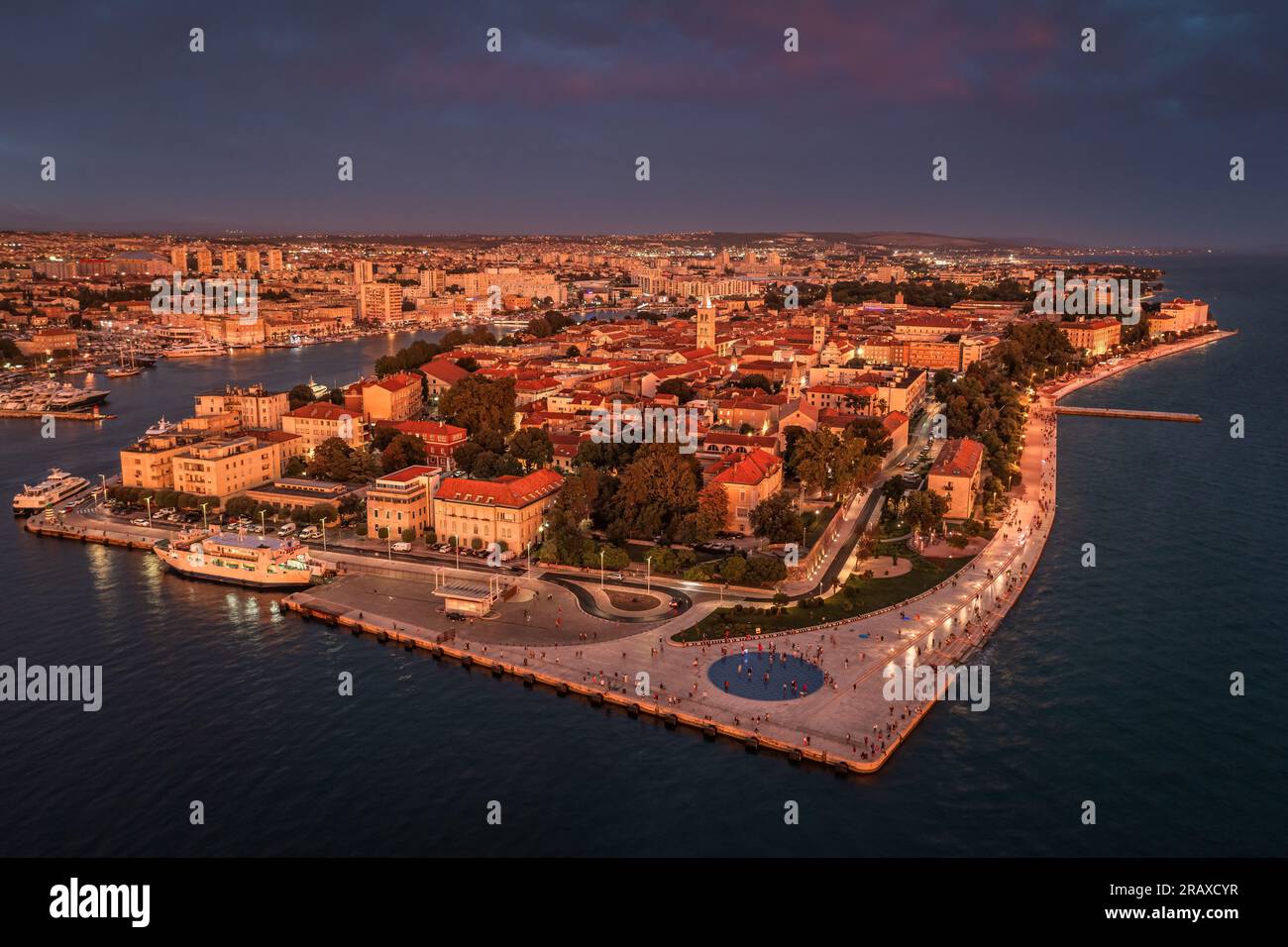 Zadar, Croatia - Aerial panoramic view of golden glowing old town of Zadar with the greeting to the sun monument, sea organ, dramatic sunset lights on Stock Photo