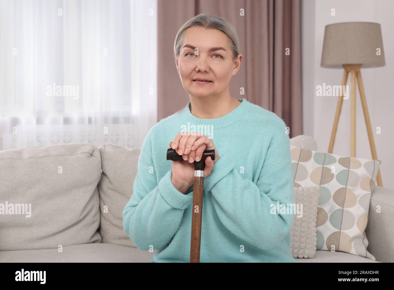 Senior woman with walking cane sitting on sofa at home Stock Photo - Alamy