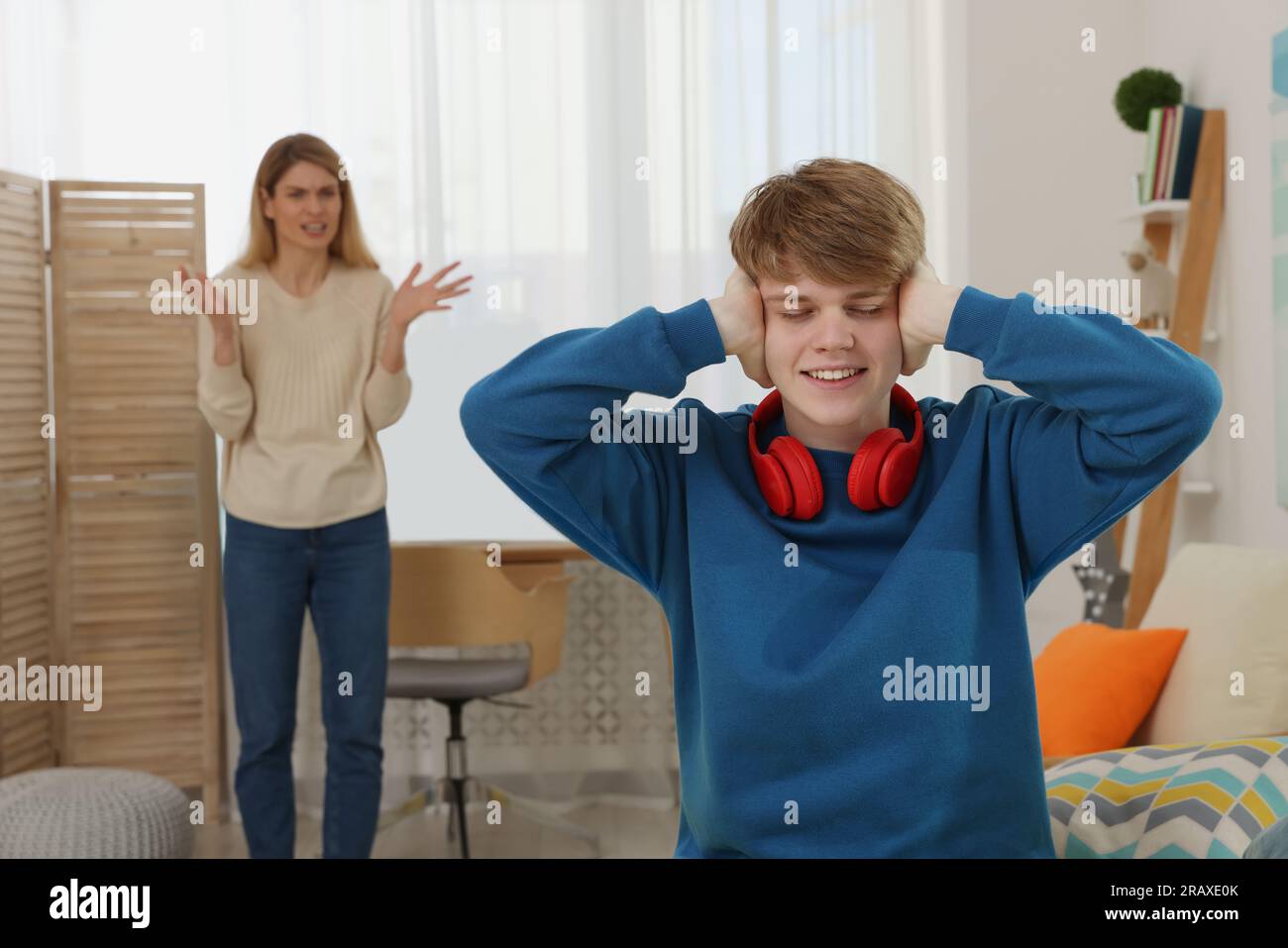 Teenage son covering his ears and ignoring mother while she scolding