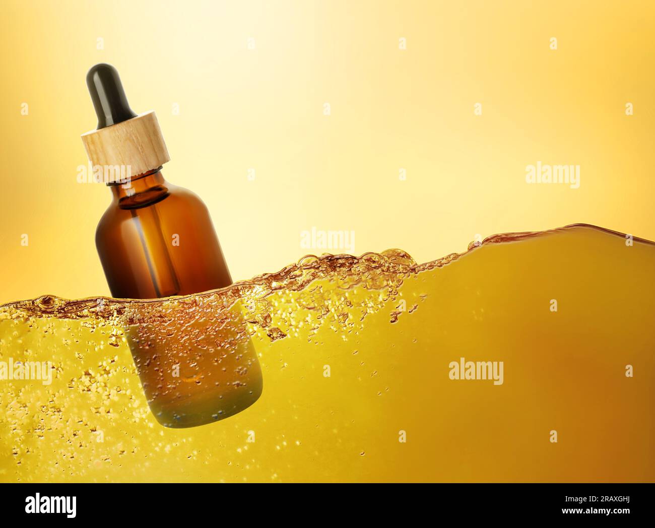 Bottle of cosmetic product floating in essential oil against gold gradient background Stock Photo