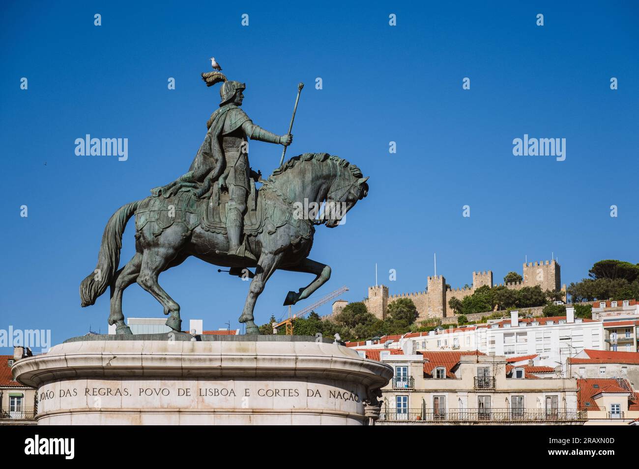 Statue of King John I standing tall in Praça da Figueira with the historic Lisbon Castle, a symbol of Portugal's rich heritage, in the background. The Stock Photo
