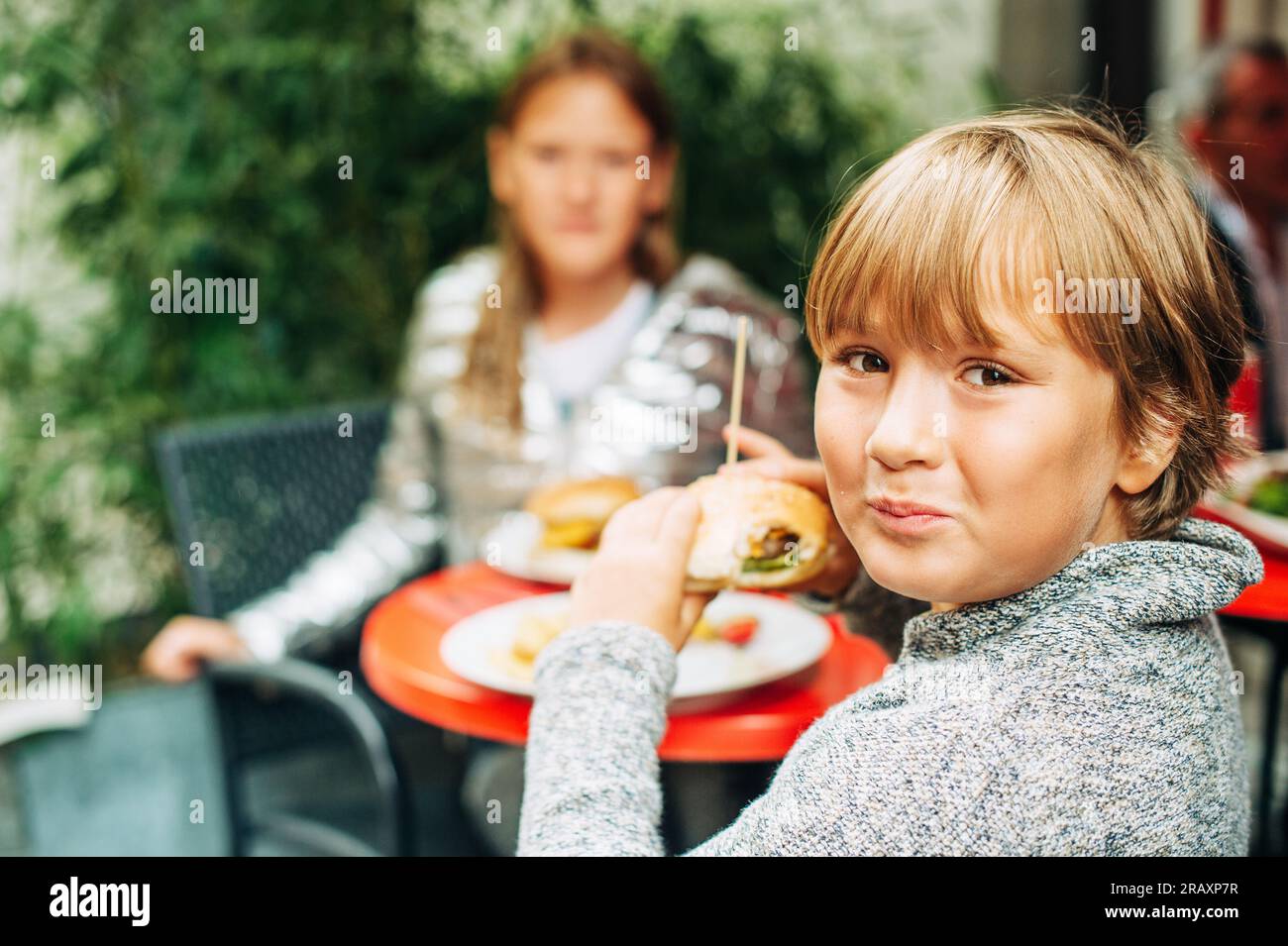 Family having lunch outside on a terrace, background with meal, children eating humburgers Stock Photo