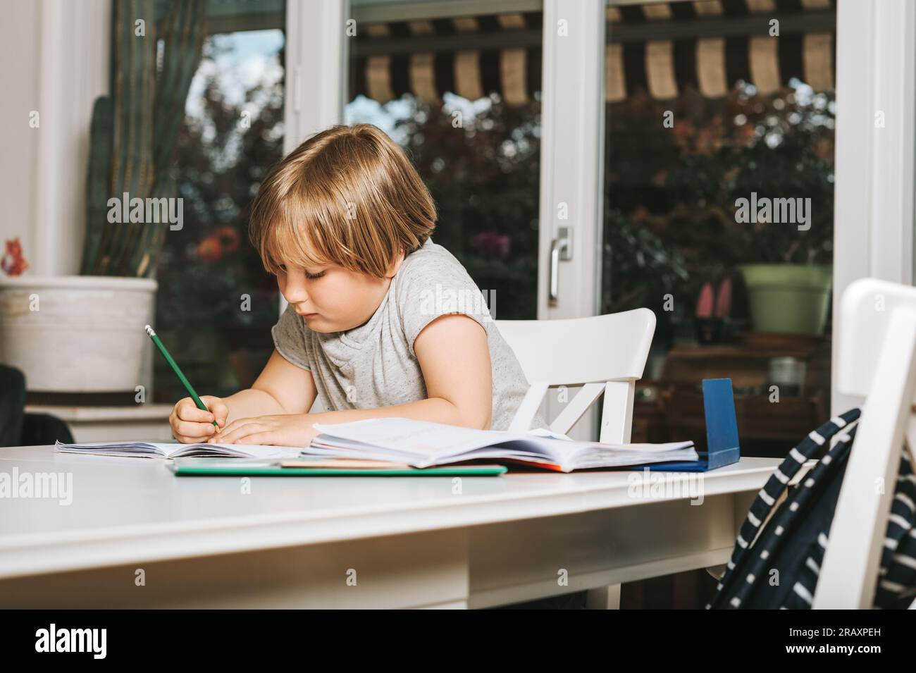 Cute little boy doing homework for school, writing in excersice ...