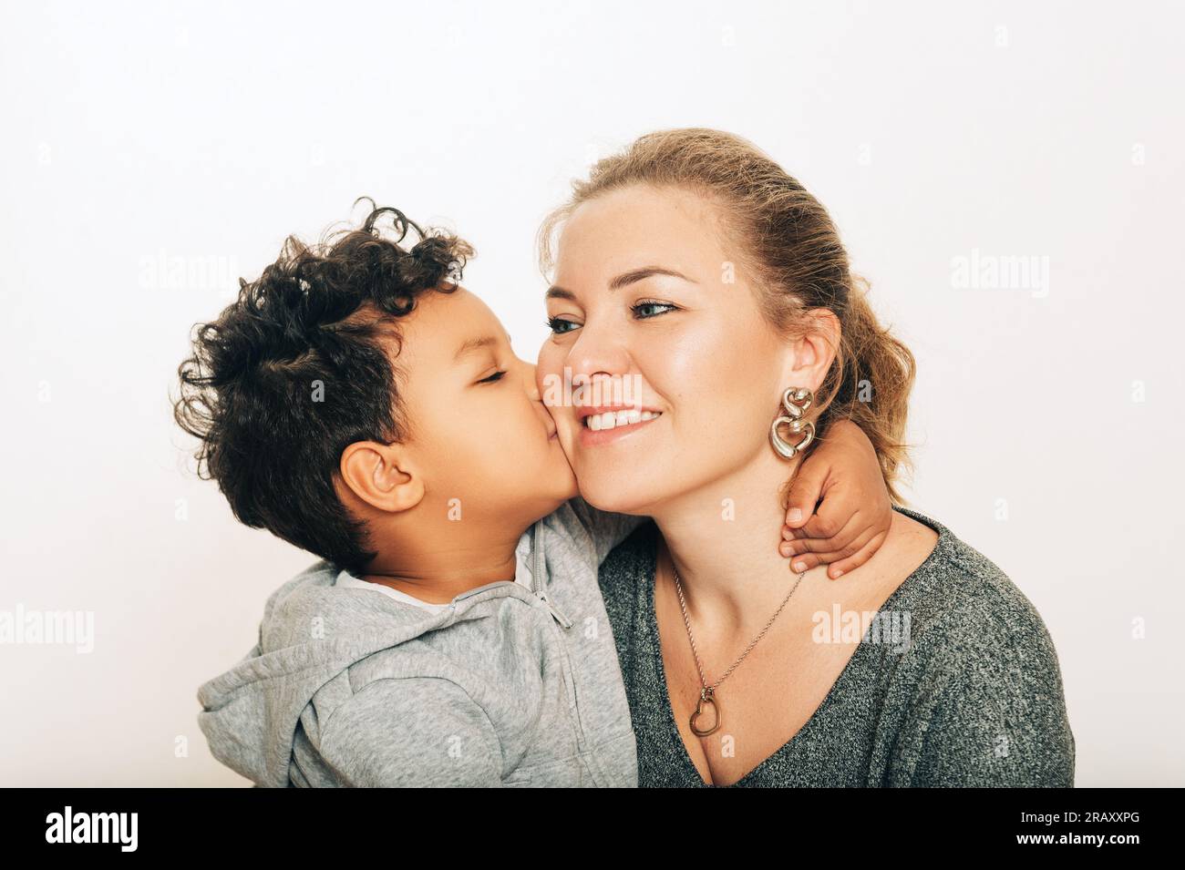 Studio shot of adorable toddler boy giving a kiss to his mother Stock