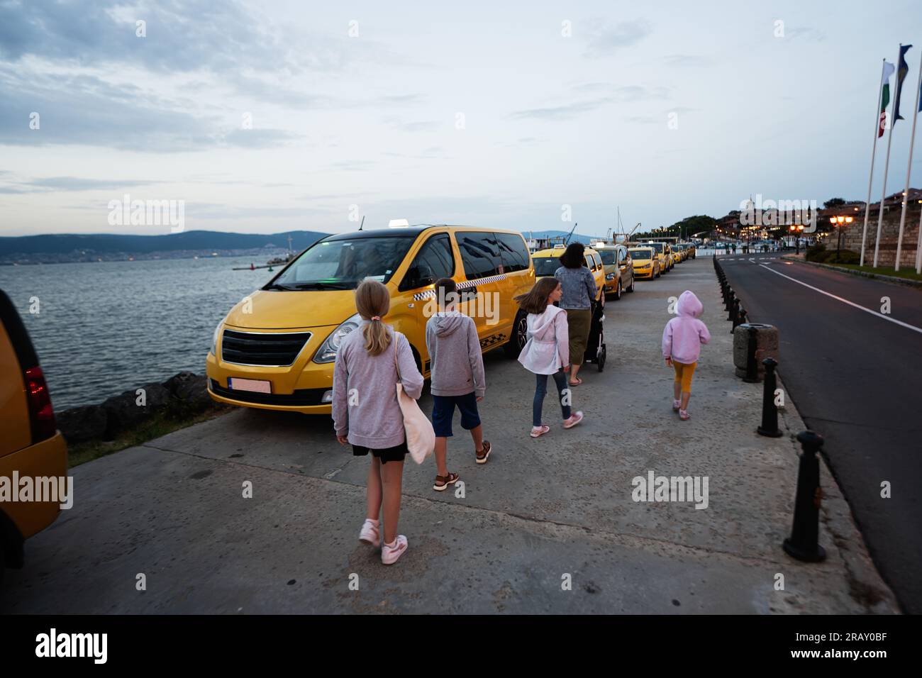 Tourists mother with kids waiting for a taxi in Nessebar, Bulgaria. Stock Photo