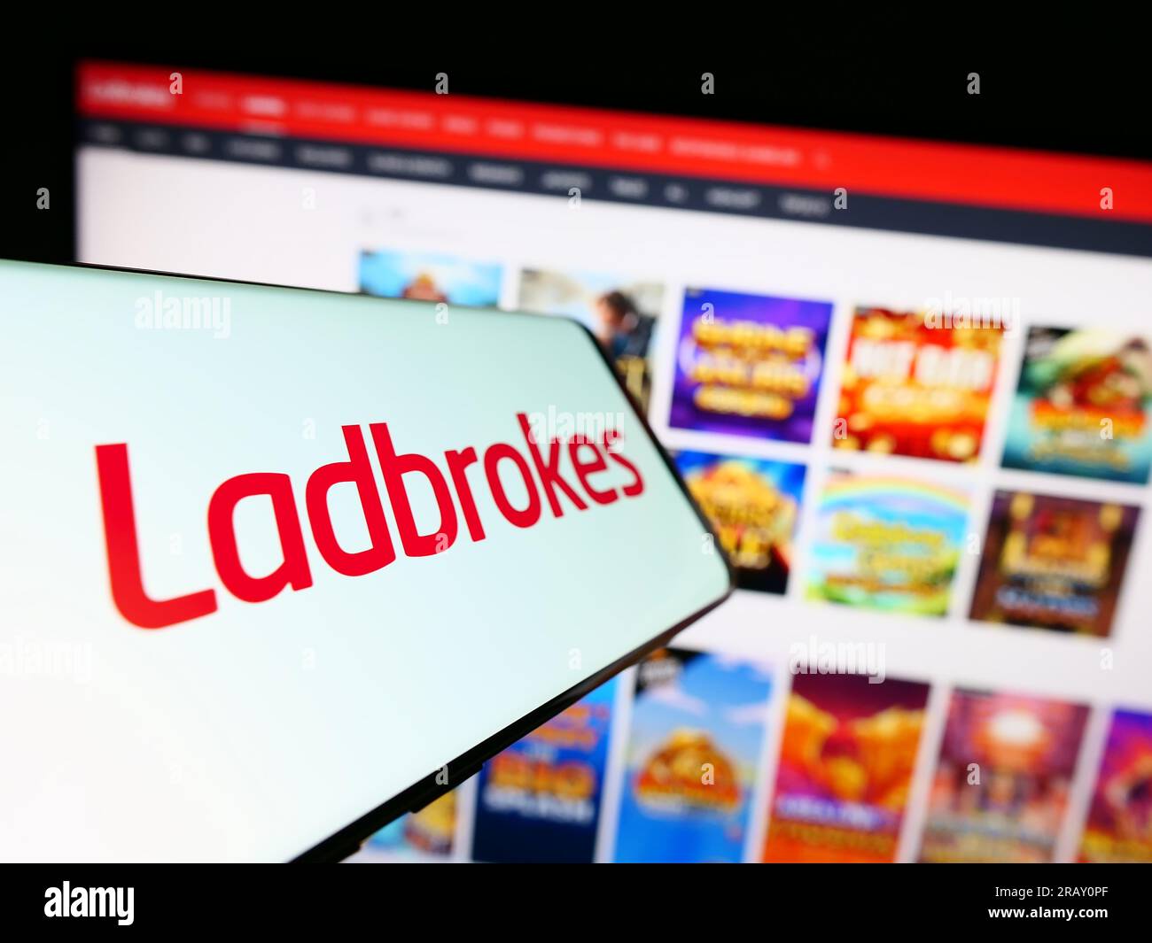 Cellphone with logo of company LC International Limited (Ladbrokes) on screen in front of website. Focus on center-left of phone display. Stock Photo