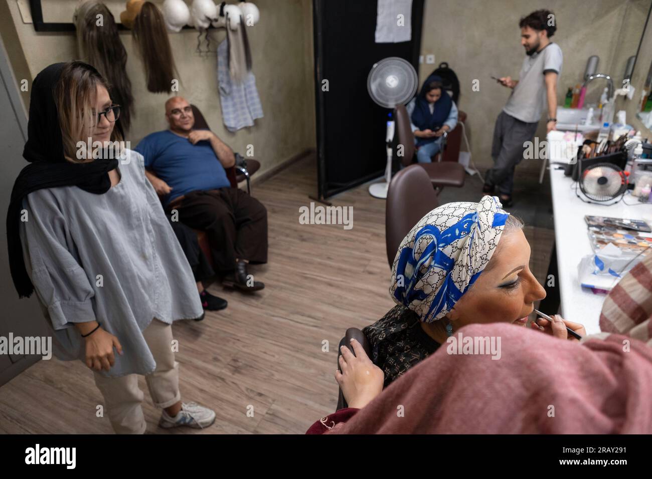 A female Iranian makeup artist is applying makeup to Iranian actress