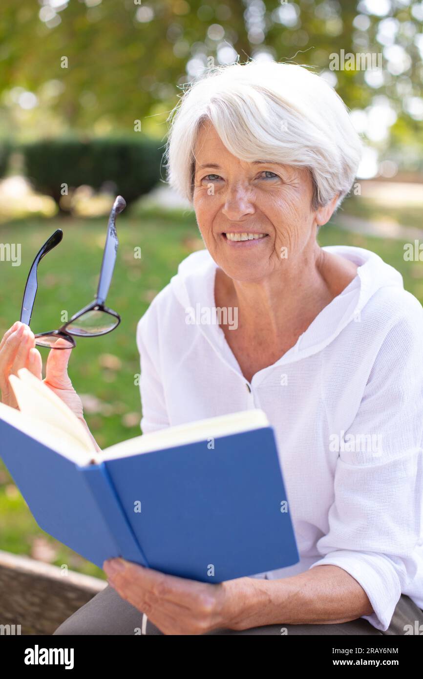 senior woman reading book laid on the grass Stock Photo - Alamy