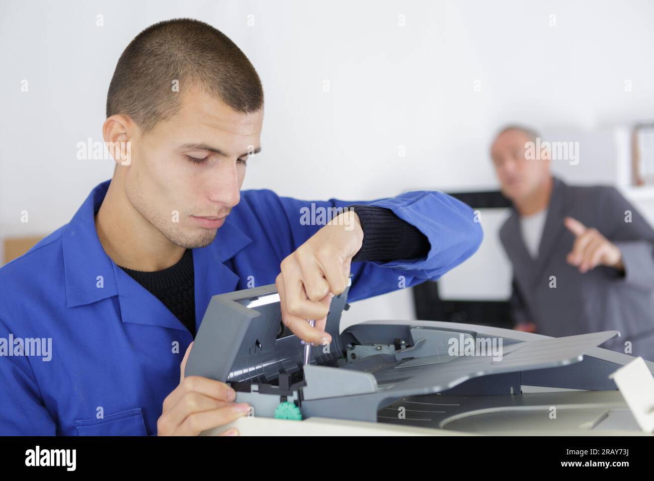 an apprentice fixing a printer Stock Photo - Alamy