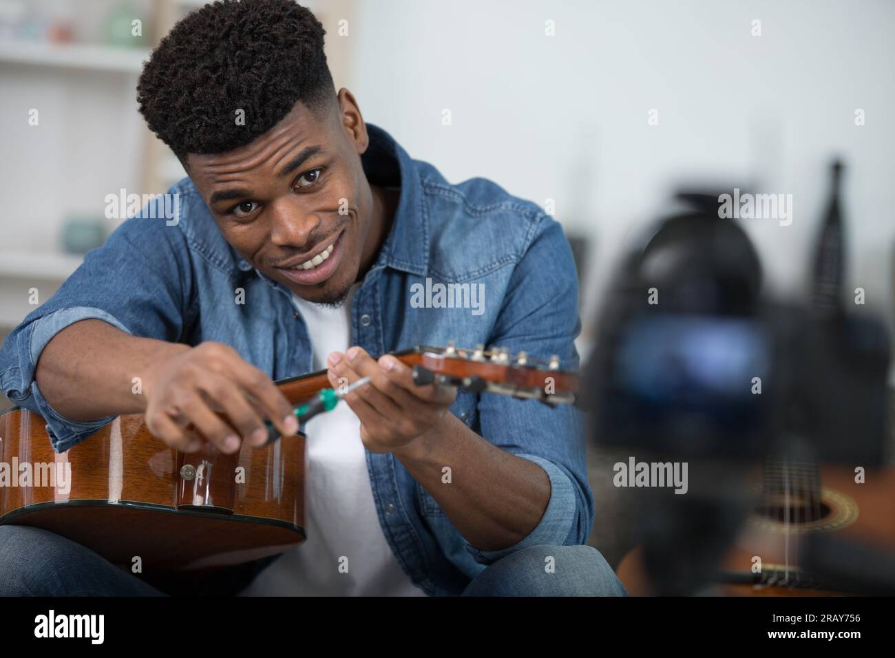 hipster filming tutorial on how to tune a guitar Stock Photo