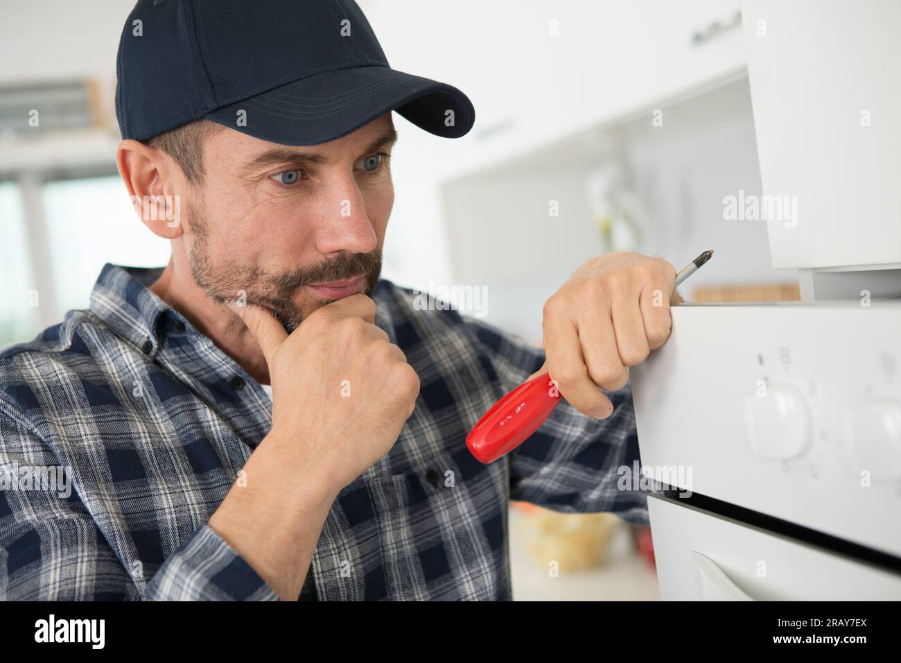 technician is fixing oven in kitchen Stock Photo