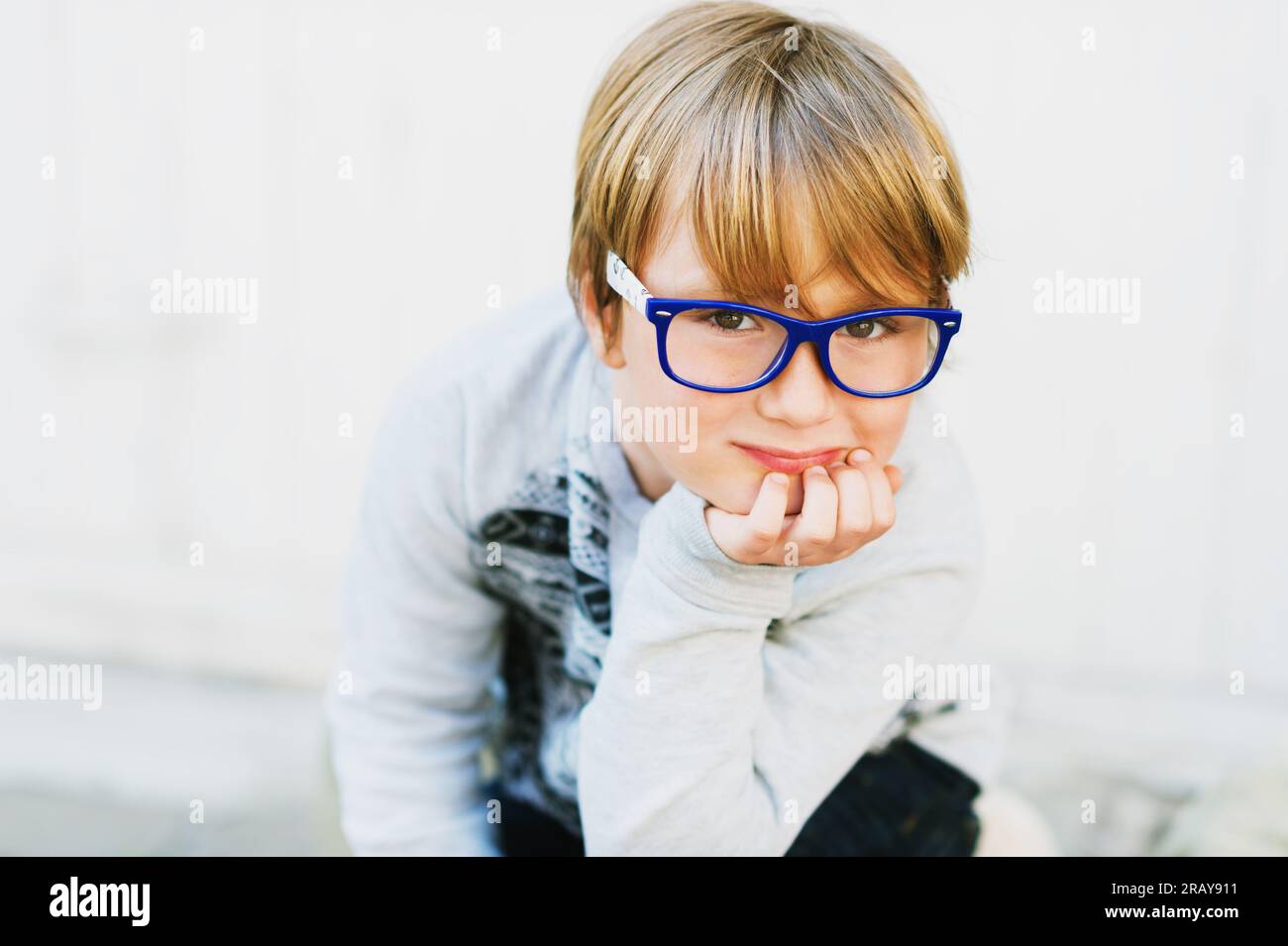 Close up portrait of adorable little kid boy wearing eyeglasses and grey sweatshirt Stock Photo