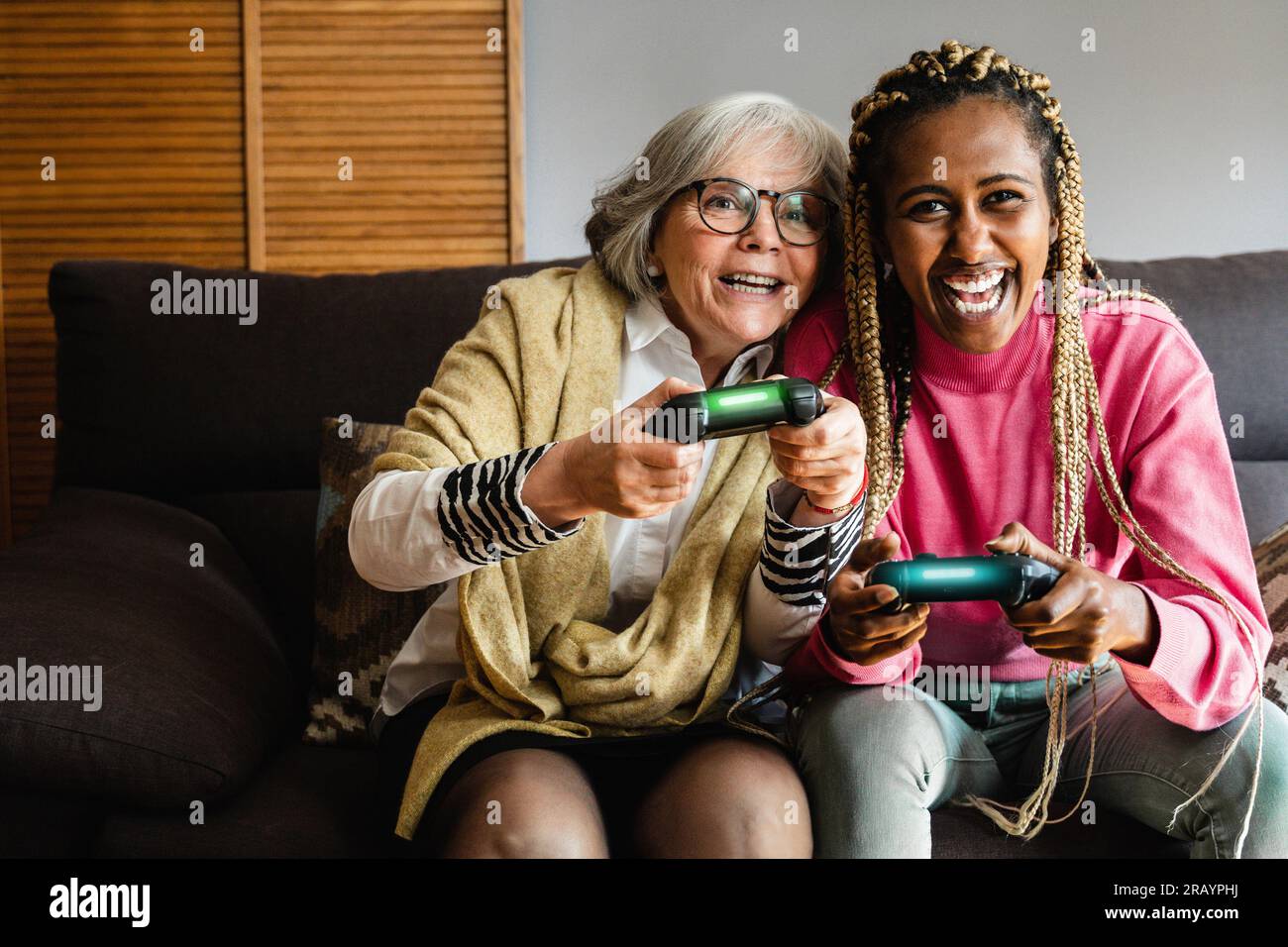 Happy multi generational women having fun playing video games together at home Stock Photo