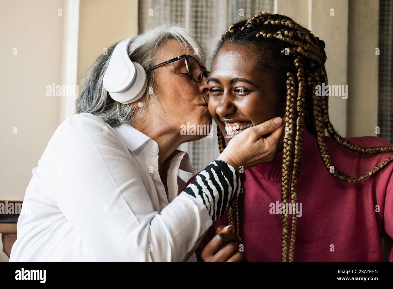 Multi generational women having tender moment at home - Care giver enjoying time with elderly senior female Stock Photo
