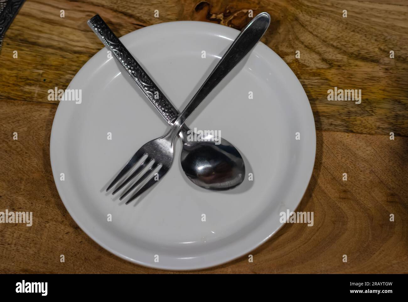 isolated white plate with spoon and fork showing no more food required Stock Photo