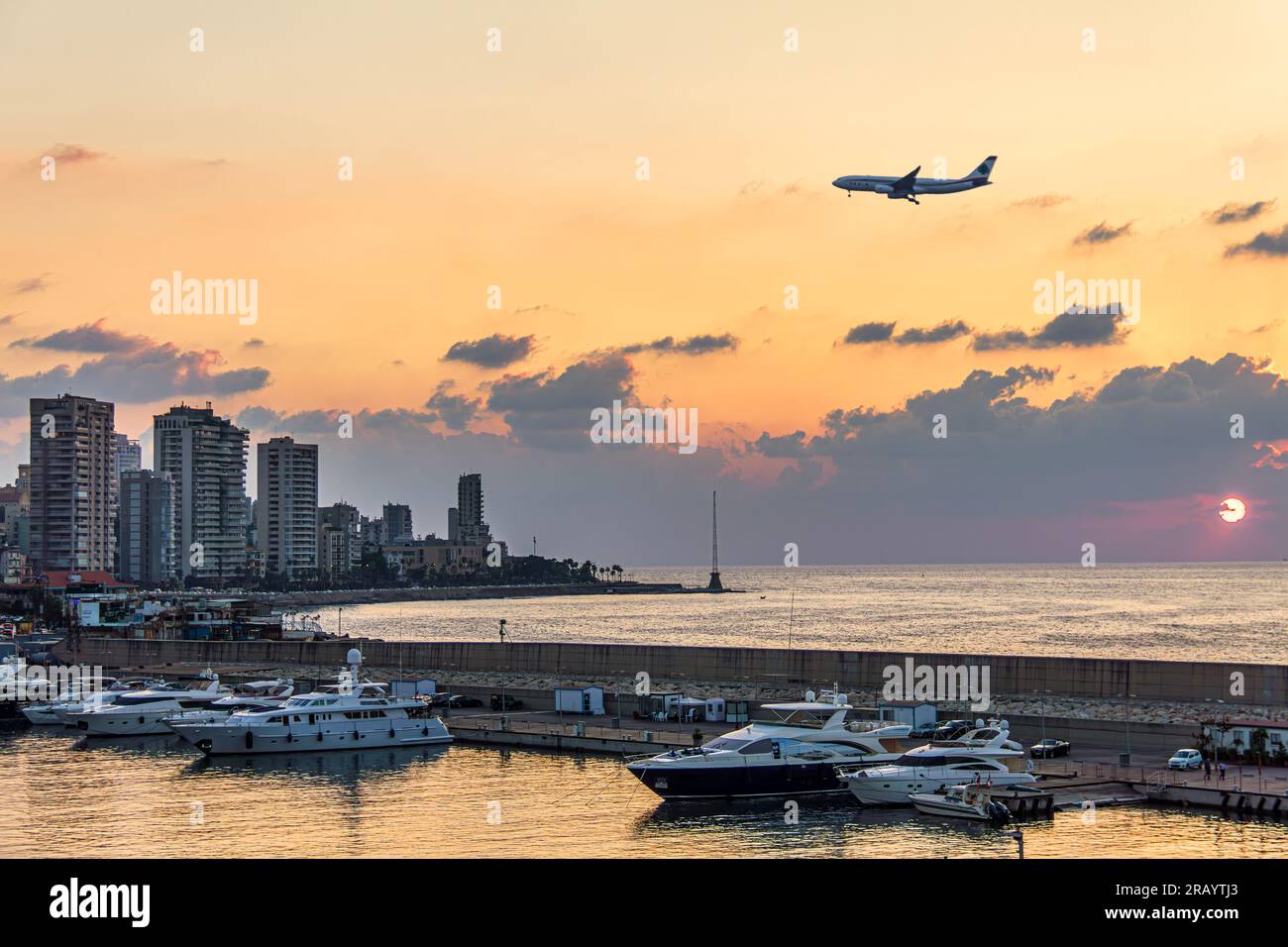 A plane landing over Beirut waterfront skyline during sunset Stock Photo