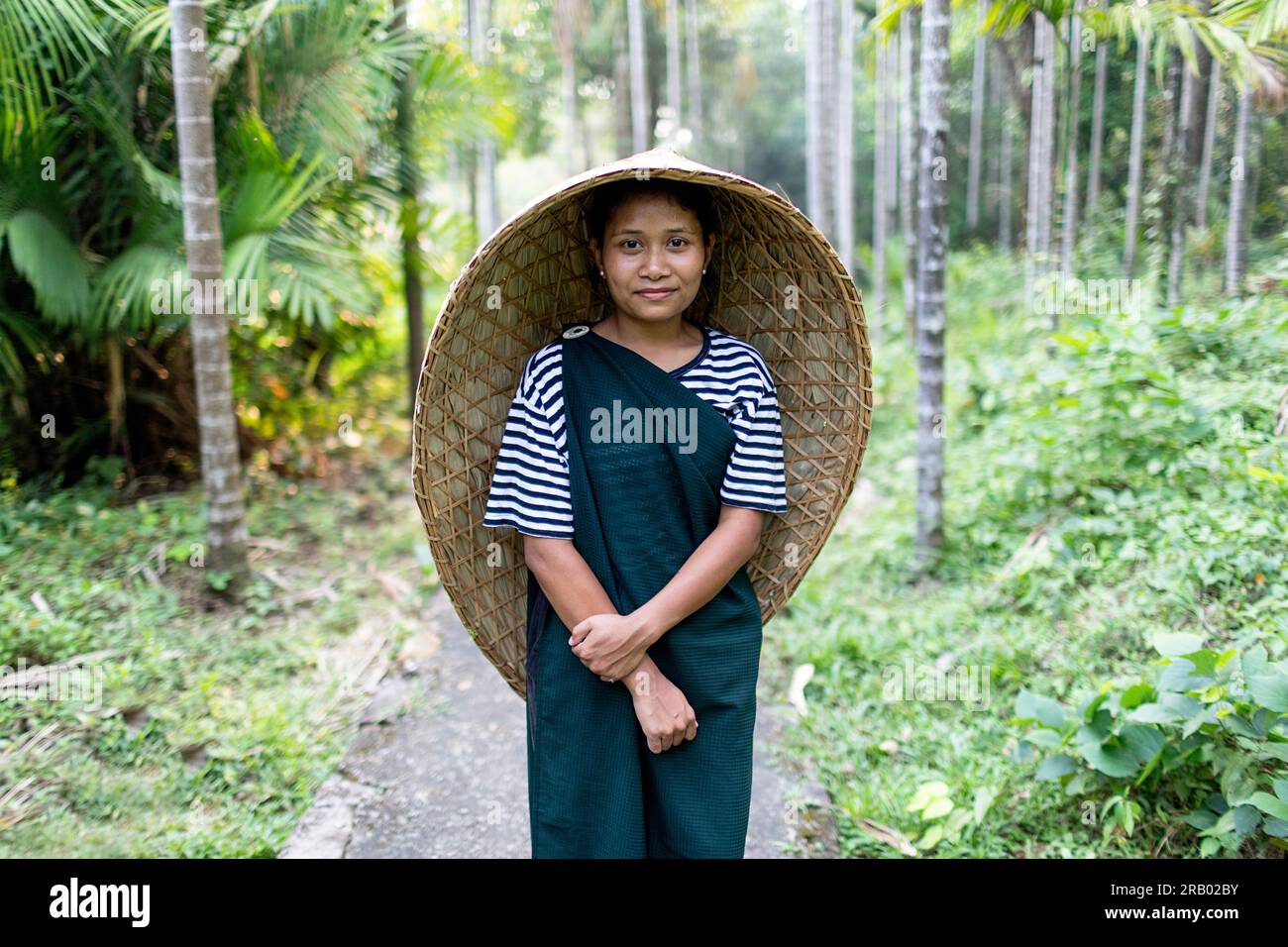 Girl from khasi tribe in traditional clothes wearing traditional rain cover made from bamboo standing between betel nut palm trees Meghalaya India Stock Photo Alamy