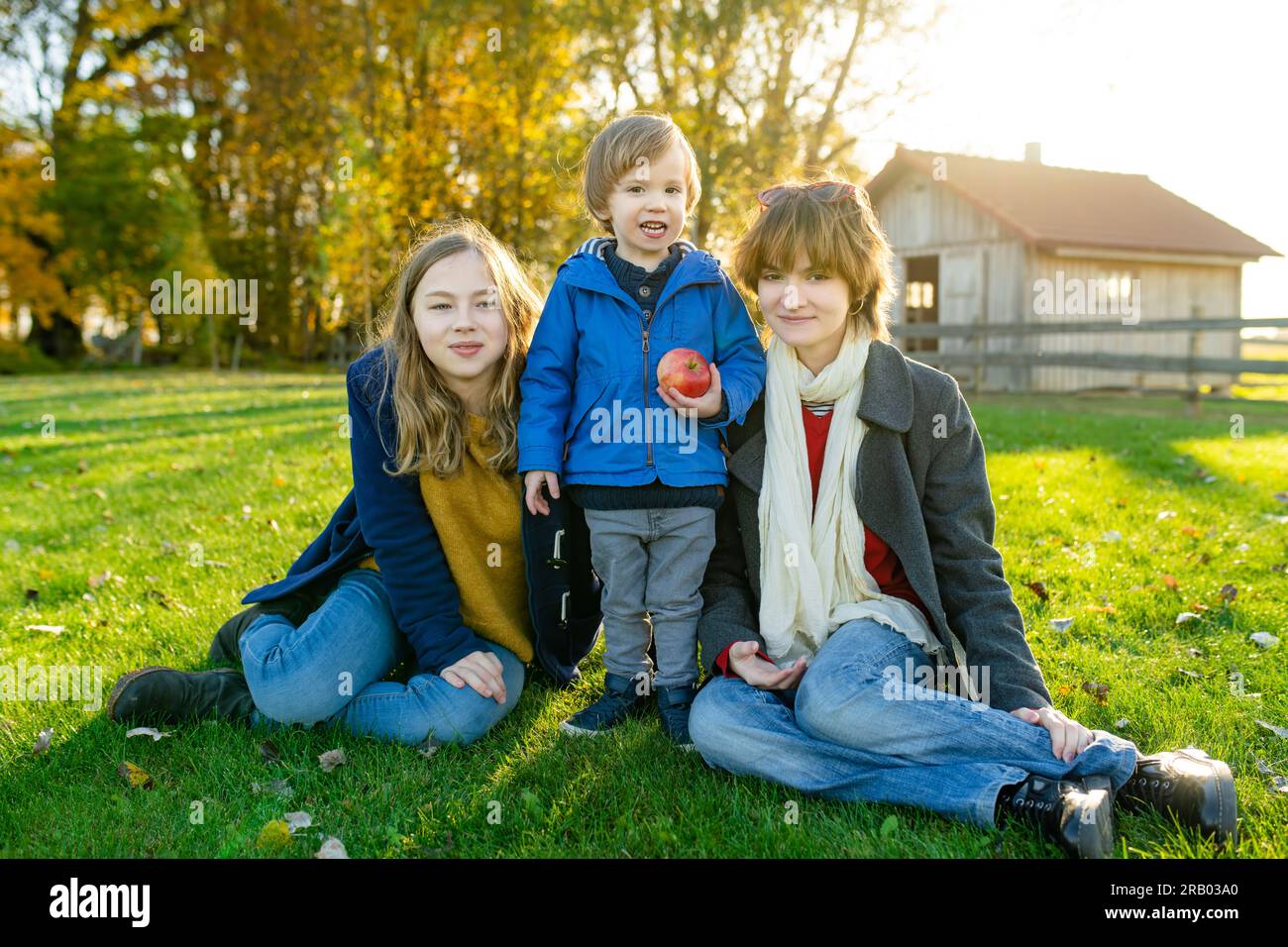 Two big sisters and their toddler brother having fun outdoors. Two