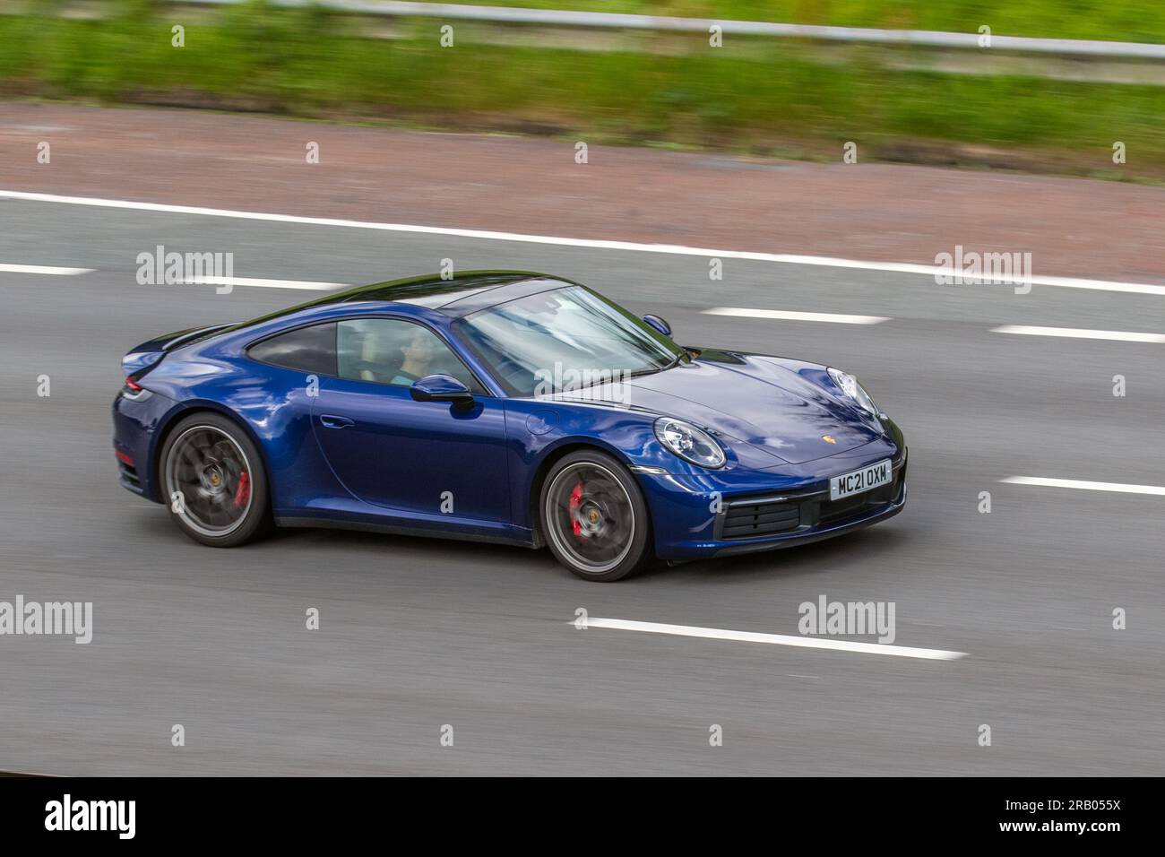 2021 Blue Porsche 911 Carrera 4S, T 450 4S Start/Stop Coupe Petrol 2981 cc, all-wheel drive; travelling at speed on the M6 motorway in Greater Manchester, UK Stock Photo