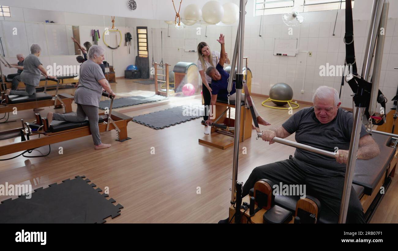 Elderly people exercising with Pilates Machines in Group Session. Female Coach Instructor guiding seniors to move and stretch body. Old age workout ro Stock Photo Alamy