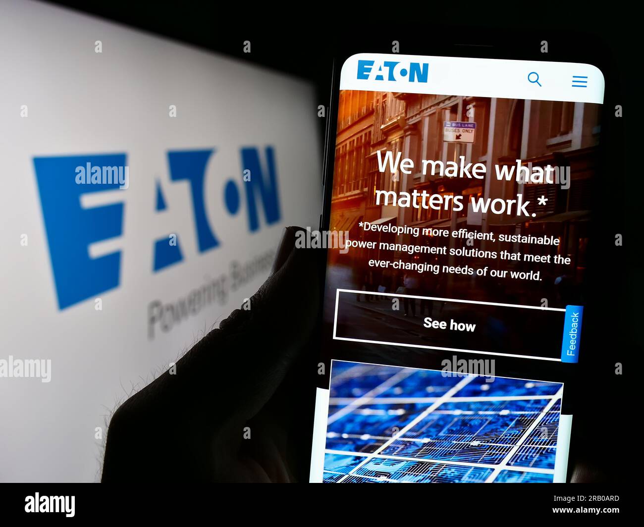 Person holding cellphone with webpage of power management company Eaton Corporation plc on screen with logo. Focus on center of phone display. Stock Photo