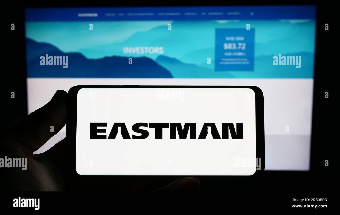 Person holding smartphone with logo of US company Eastman Chemical Company on screen in front of website. Focus on phone display. Stock Photo