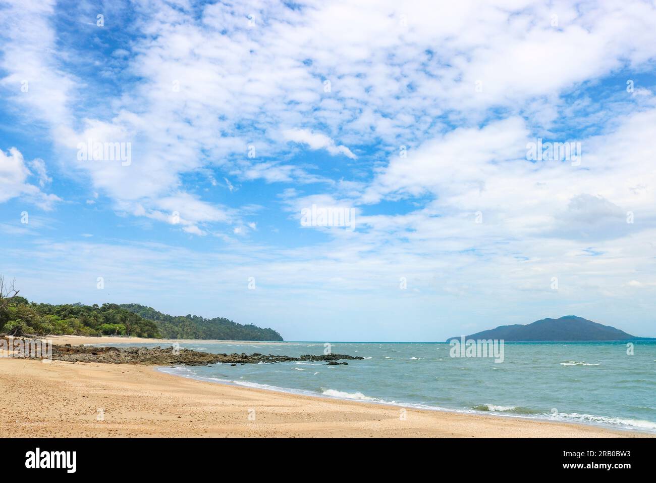 Tropical sandy rocky beach with clear clear blue water under a blue sky ...